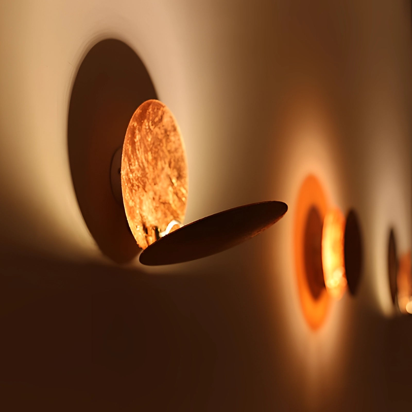 Luxury gold moon-phase wall light with an amber and orange glow, circular design against a wooden background, resembling an astronomical object in the sky, artistic and elegant sconce.