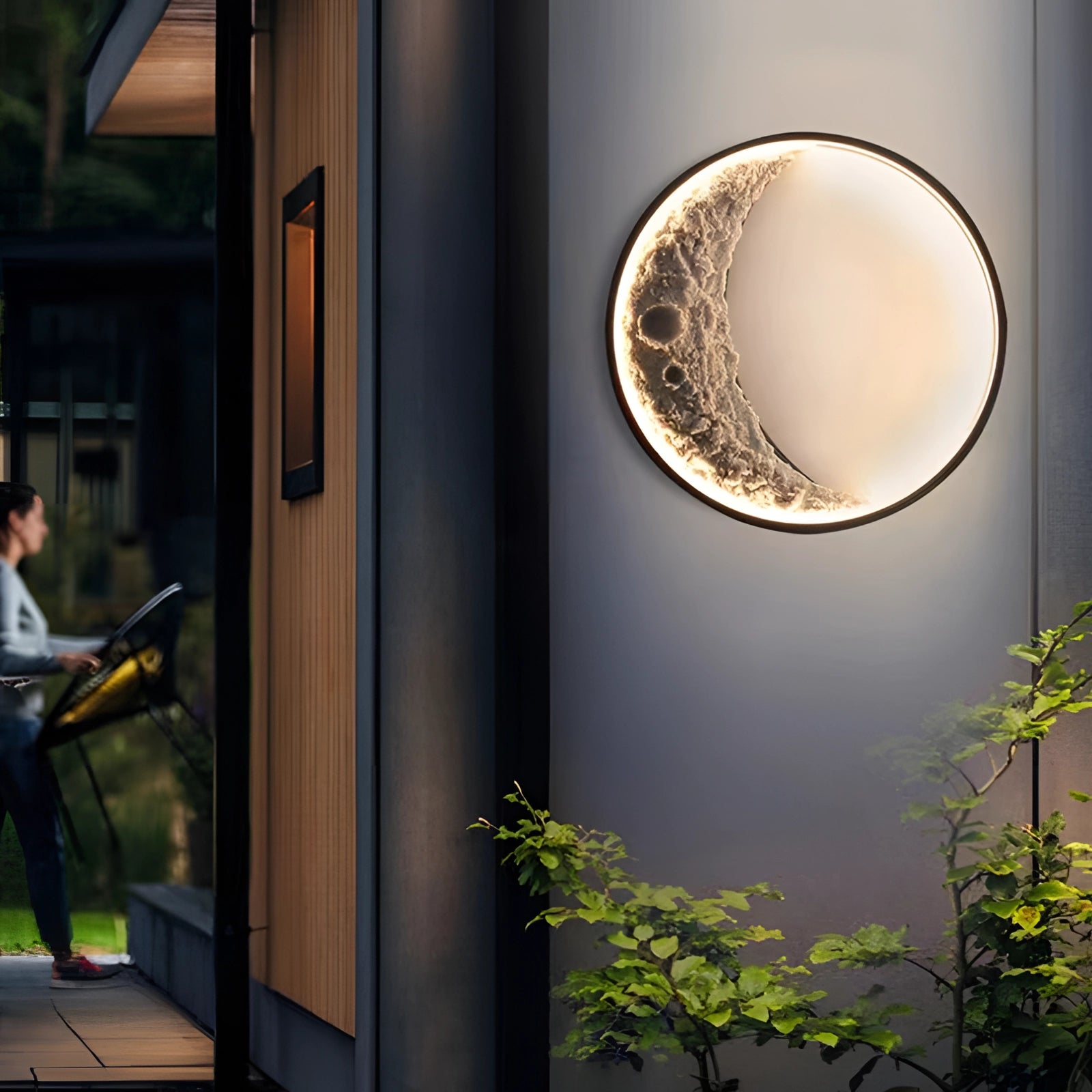 Moon phase wall lights with celestial crescent design, illuminating a room with ambient lighting; surrounded by greenery, wood accents, and sunlight streaming through a window.
