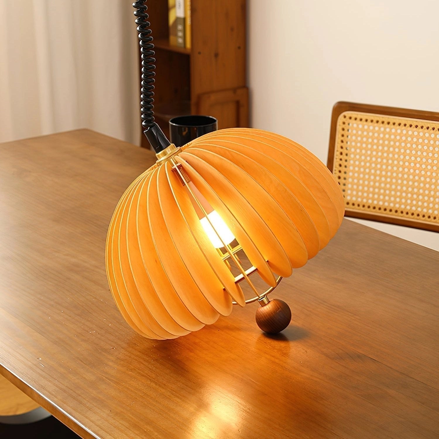 Orange Scandinavian ribbed pendant light hanging above a wooden table, featuring a modern design with a warm, cozy ambiance reminiscent of a pumpkin shape, suitable for kitchen lighting.