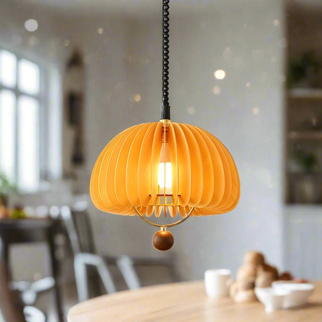 Orange Scandinavian ribbed pendant light hanging above a wooden table and chairs in a modern kitchen interior with large windows.
