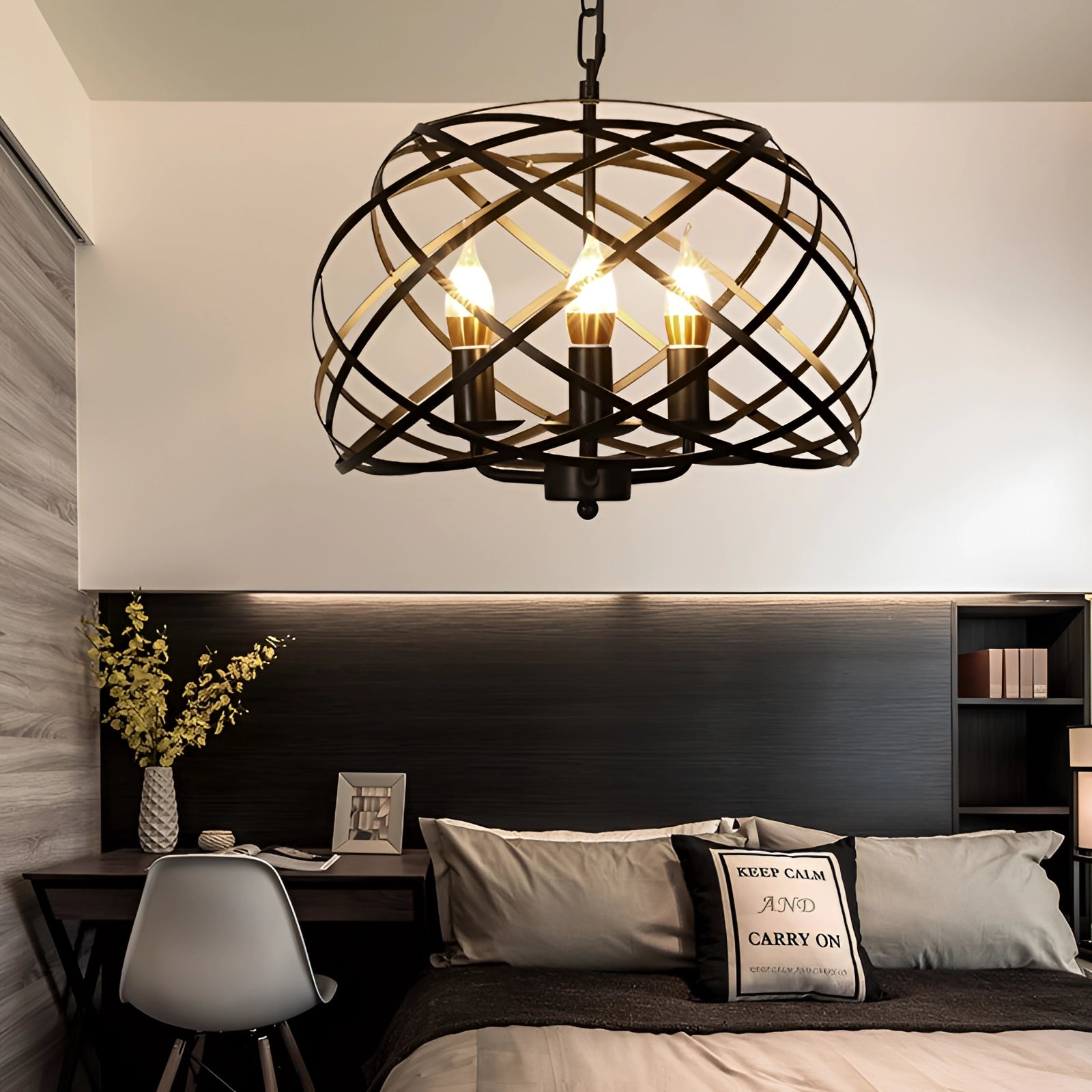 Black metal orb chandelier with an industrial design, featuring a cage-like structure. The pendant light is hanging in a cozy interior setting, providing warm yellow illumination to the surrounding furniture and decor.