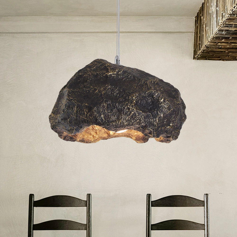 Organic stone pendant light with a modern industrial design, featuring a black and wood finish with metal accents, casting warm tints and shades.