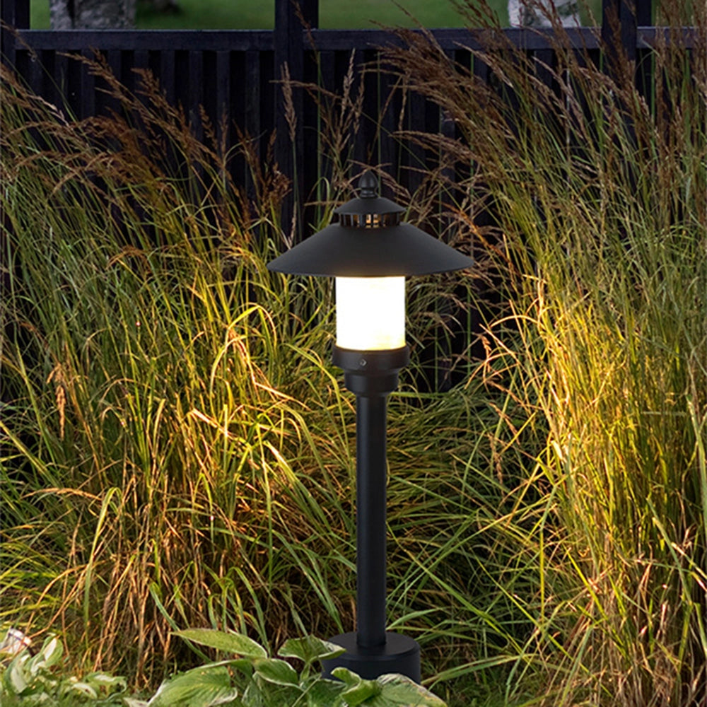 Pagoda-inspired outdoor path light illuminating a garden pathway surrounded by various plants and greenery.