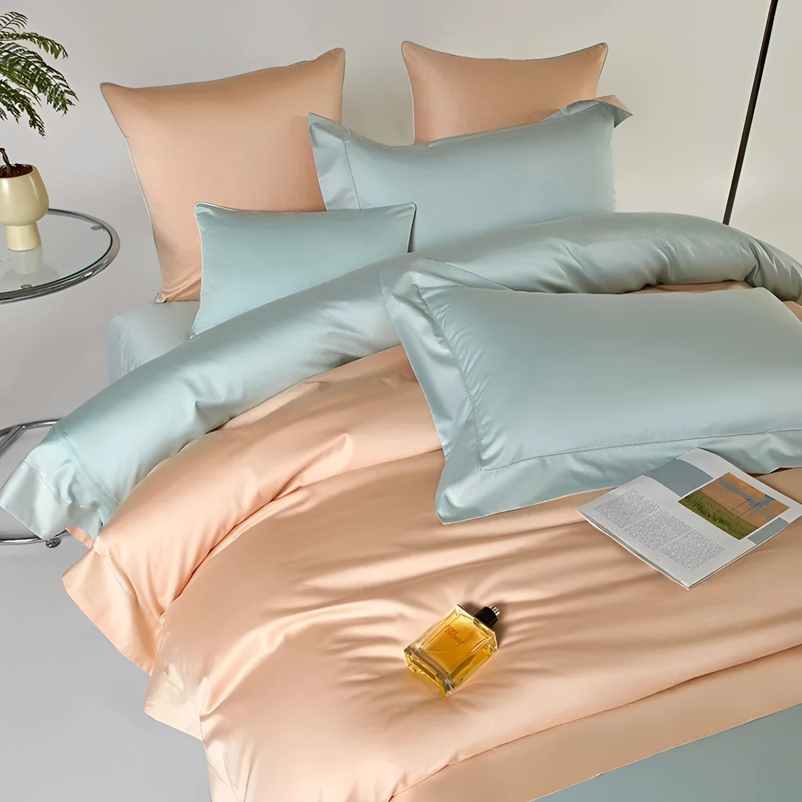Pastel reversible satin duvet set in peach and aqua displayed on a neatly made bed with matching pillowcases, showcasing its lightweight and comfortable texture in a cozy bedroom setting.