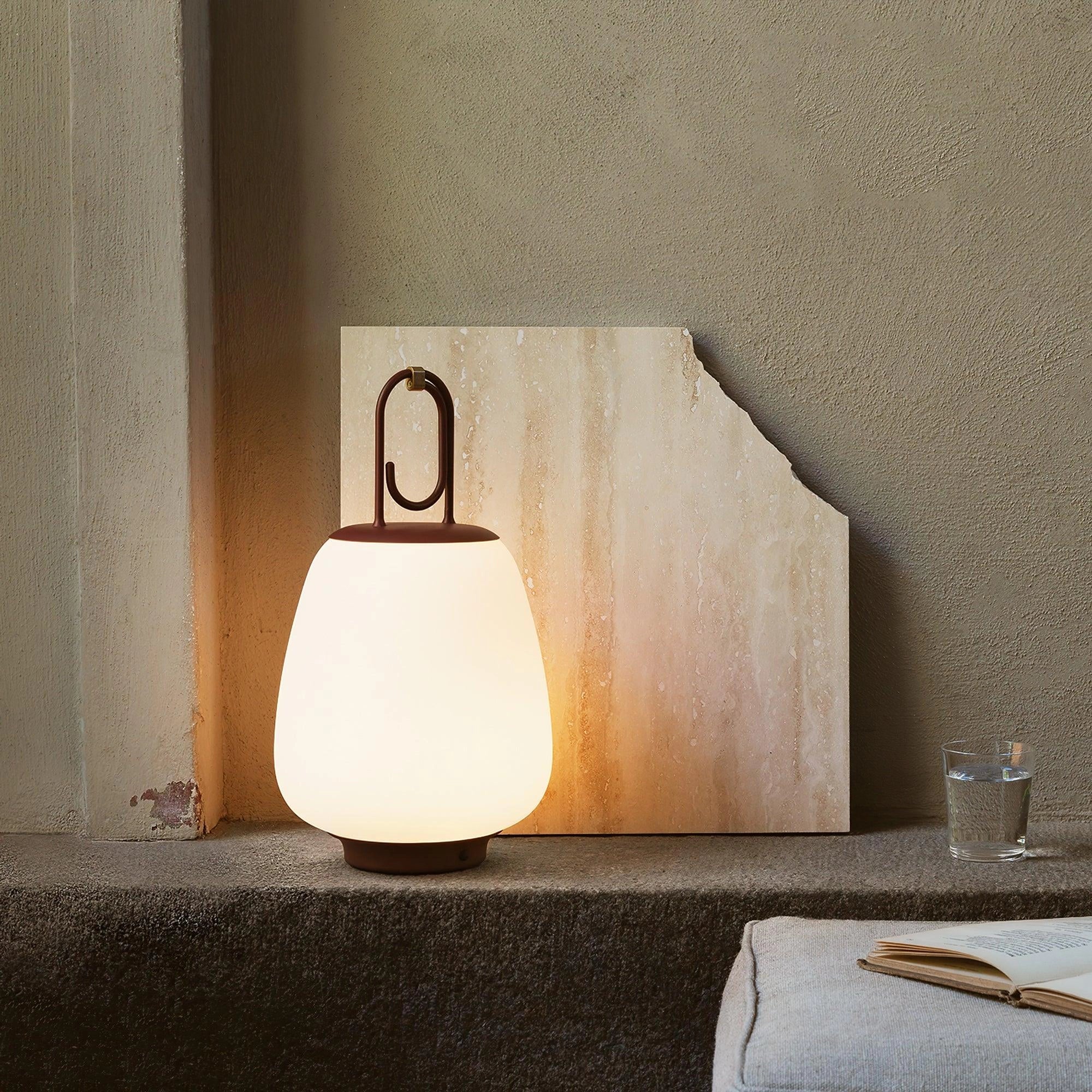 Portable rechargeable LED table lamp with a modern minimalist design, placed on a wooden floor.