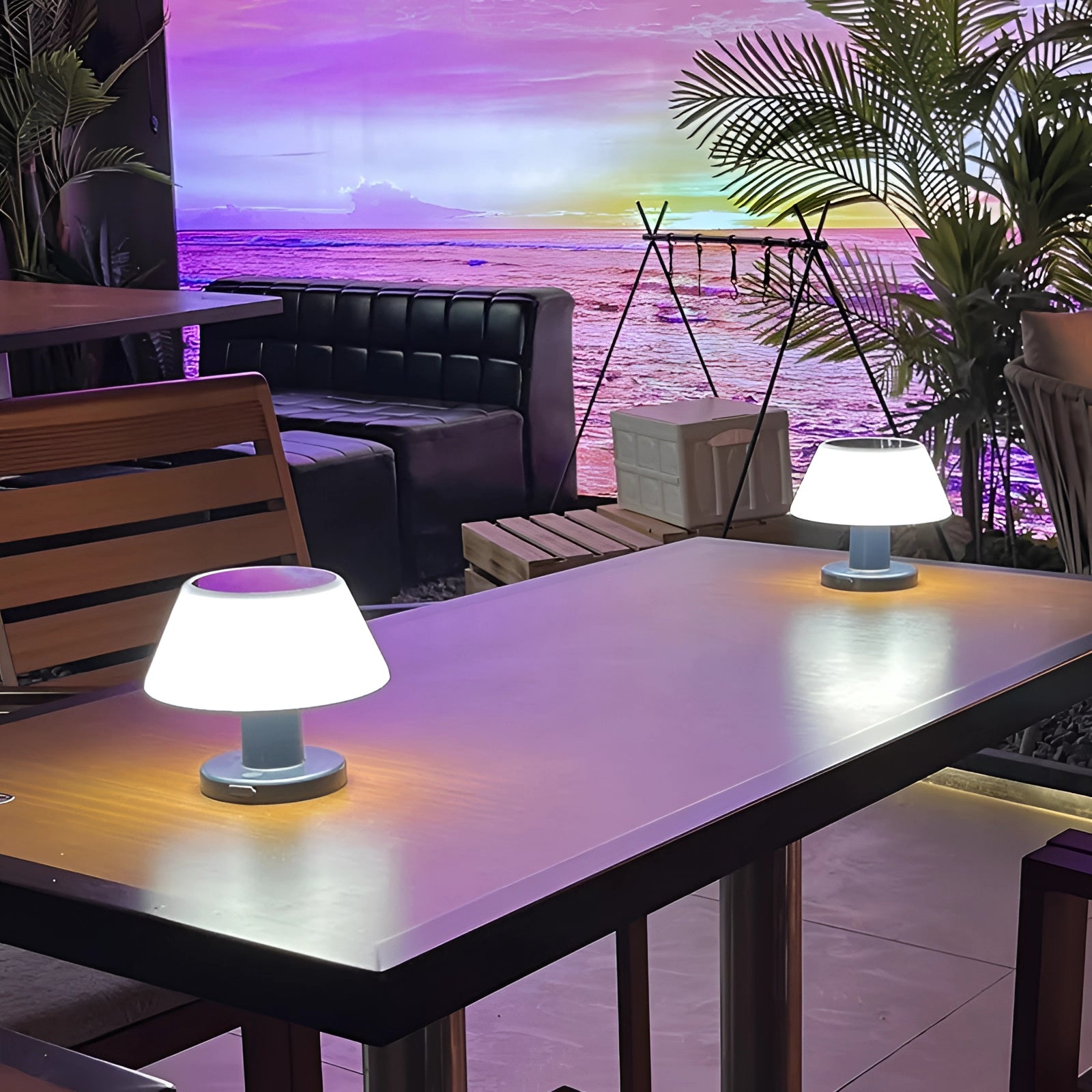 Rechargeable cordless LED table lamp with a blue base, placed on a dining table in a modern interior setting, featuring adjustable brightness.