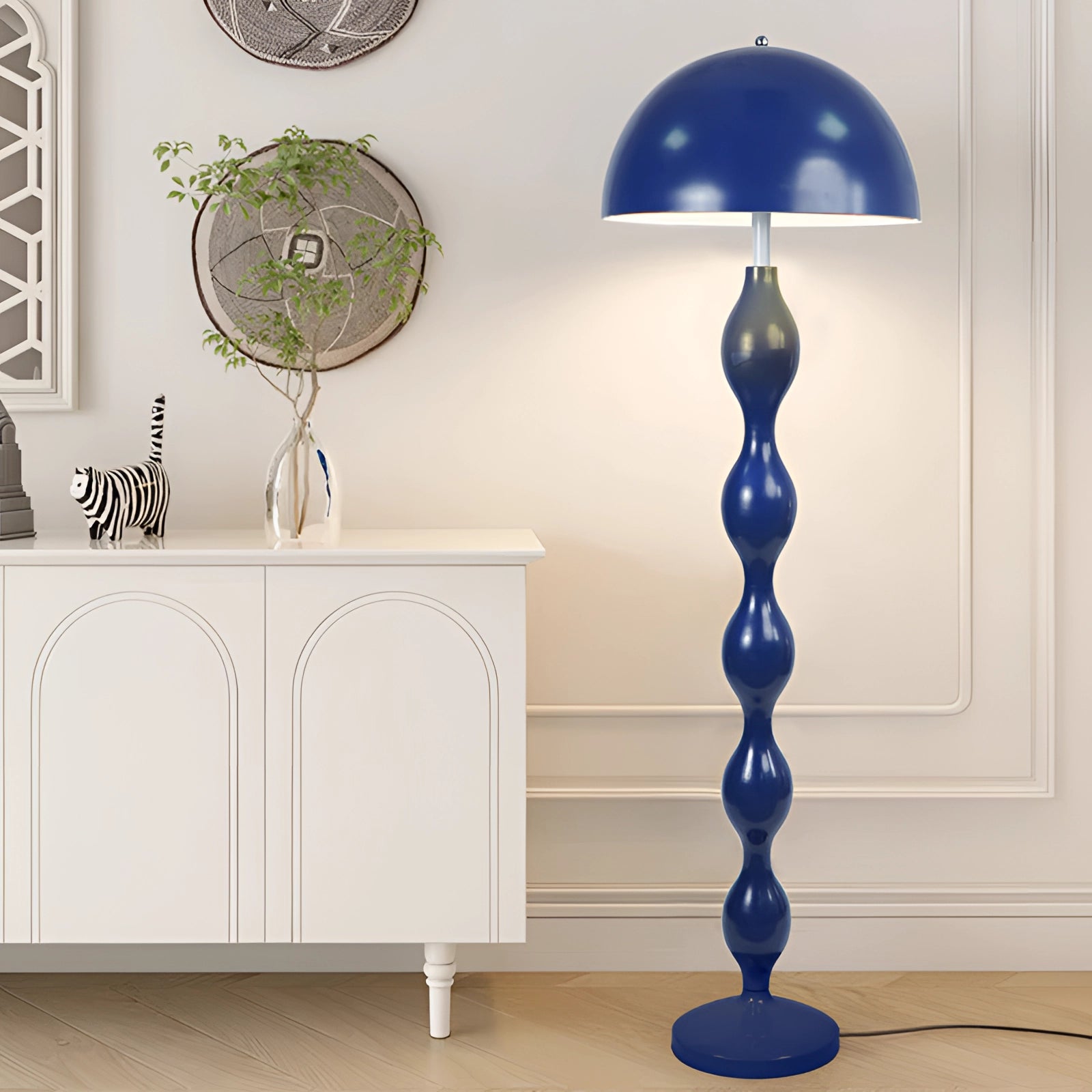 Modern wavy design red floor lamp with contemporary sculptural lighting placed near a white table and wooden shelving unit.