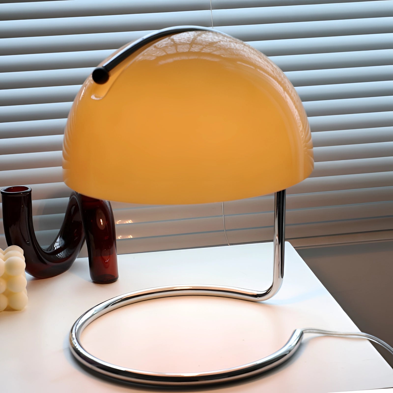 Mid-century modern desk lamp with a retro yellow and orange chrome design, featuring elegant lighting and metal construction, set against a wooden surface.