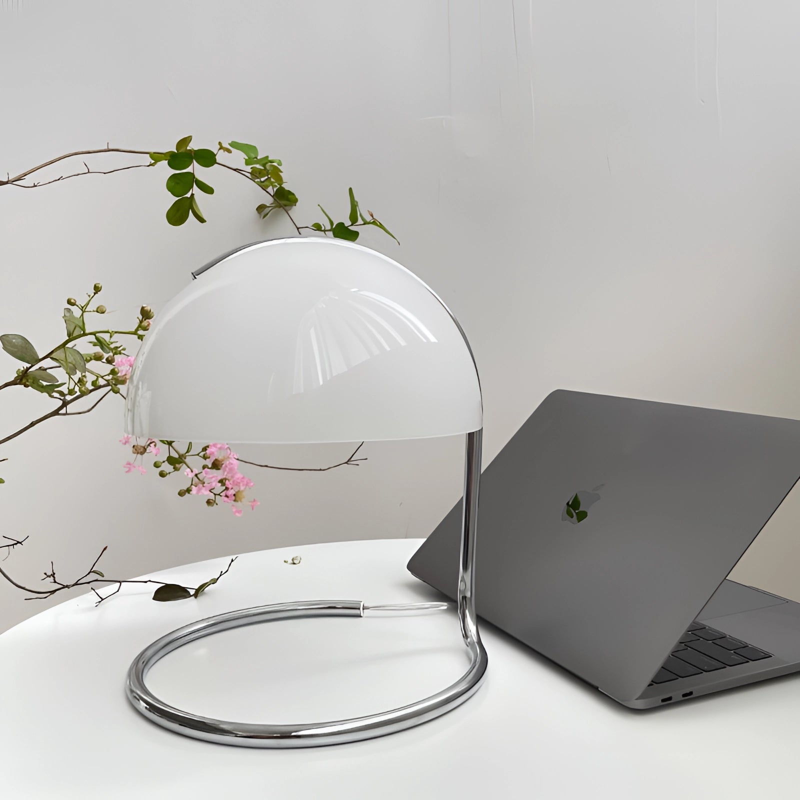 Retro yellow chrome mid-century desk lamp on a desk alongside a laptop, surrounded by various houseplants and dishware, creating an elegant and stylish workspace setting.