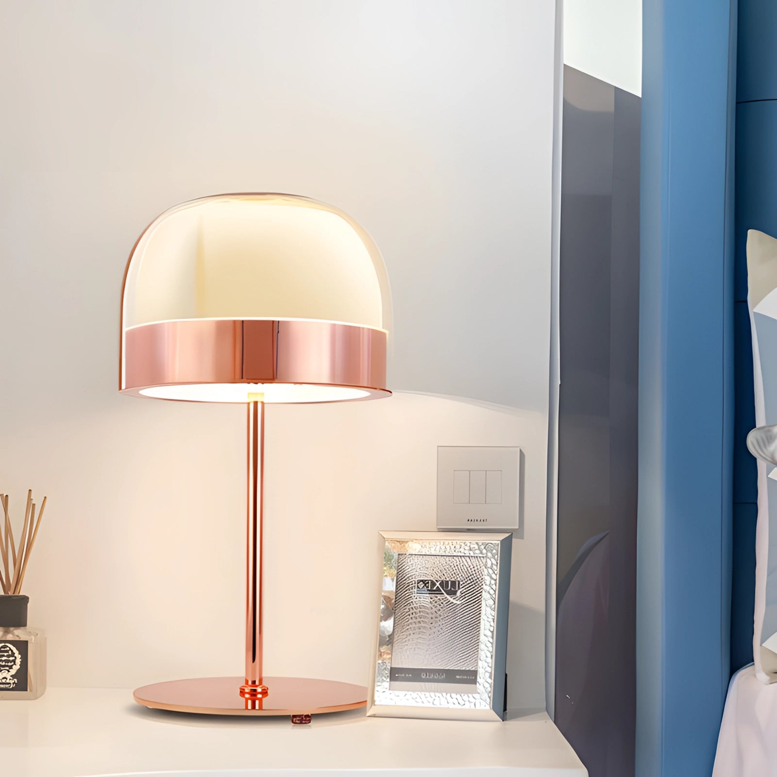 A rose gold minimalist desk lamp with a modern metal finish, displayed on a wooden table, featuring a sleek design suitable for office decor. The lamp has a soft pink hue, contributing to its elegant aesthetic.