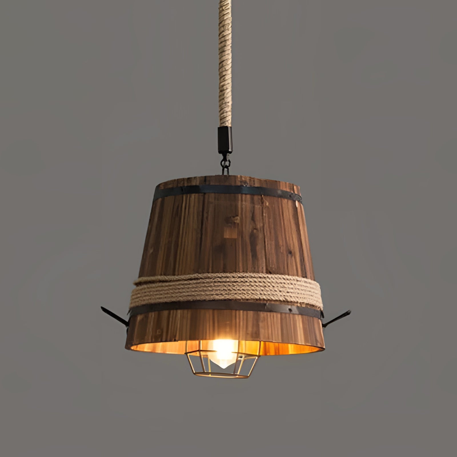 Rustic barrel pendant light with eco-friendly farmhouse design, featuring metal construction and ceiling fixture, hanging indoors illuminating with a warm light bulb.