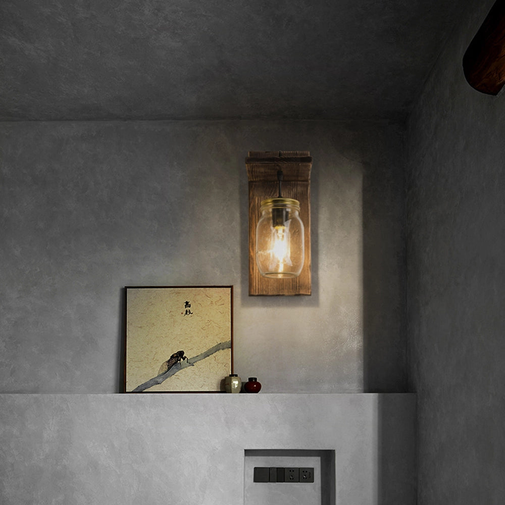 Rustic mason jar wood wall sconce attached to a wooden wall, featuring vintage farmhouse lighting design elements.