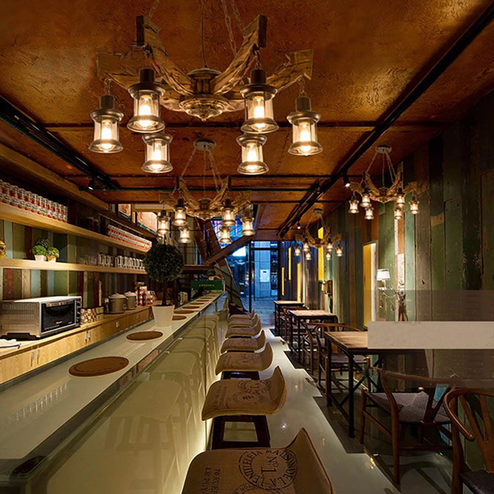 Rustic metal and wood chandelier hanging from the ceiling, illuminating a cozy cabin interior with symmetrical design elements and wooden decor.