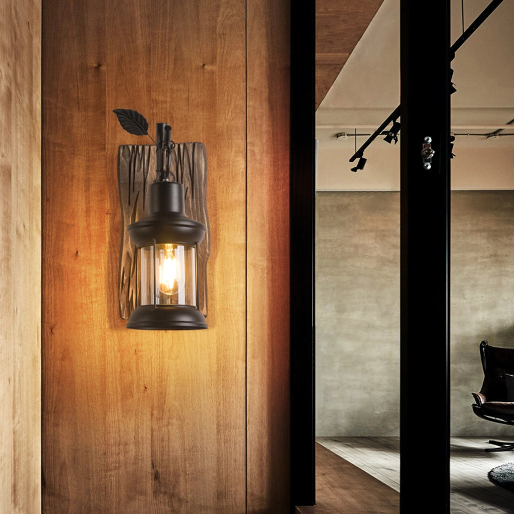 Rustic vintage lantern sconce with a wooden mount, featuring a glass shade and metal lantern design, mounted near a window in an interior setting, evoking a cozy cabin atmosphere.