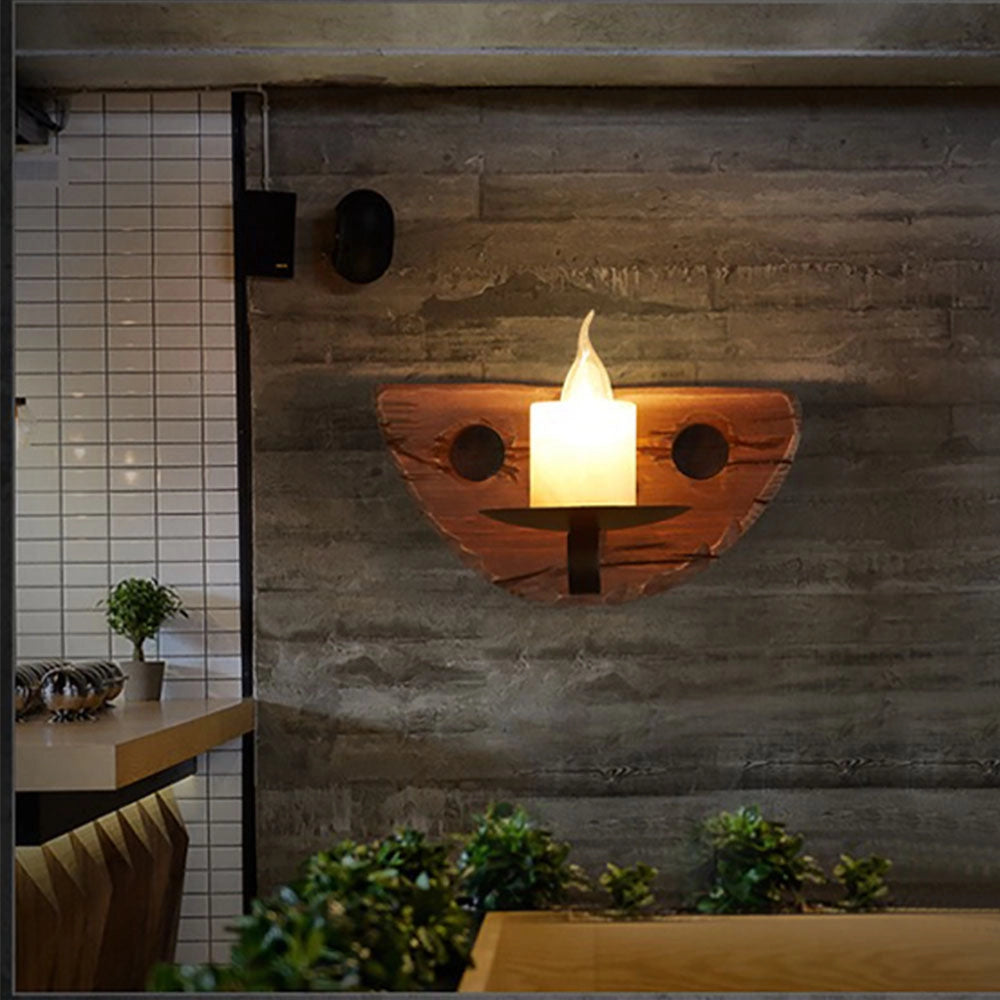 Rustic wooden wall sconce designed as a vintage candle holder, featuring a farmhouse decor style with a rectangular wooden frame mounted on a brick wall, surrounded by greenery.