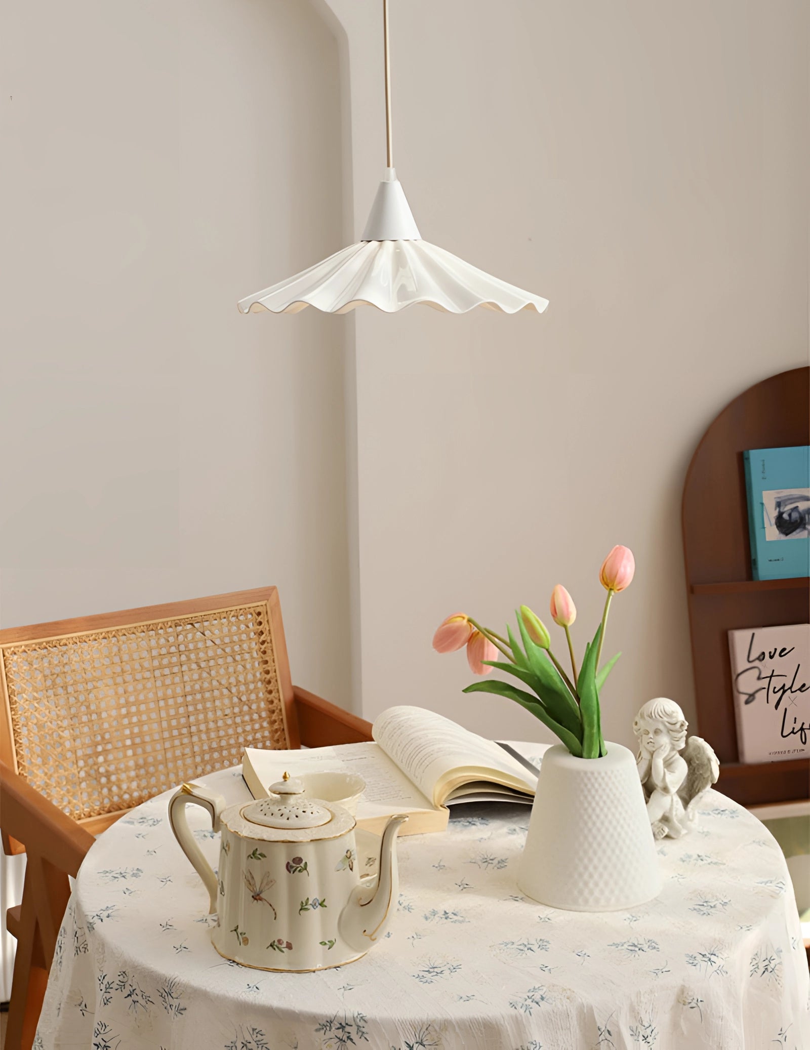 Modern scallop-edged LED pendant light hanging from the ceiling, illuminating a stylishly set dining table with tableware, dishware, and an elegant tablecloth, creating a warm and inviting atmosphere in the interior space.