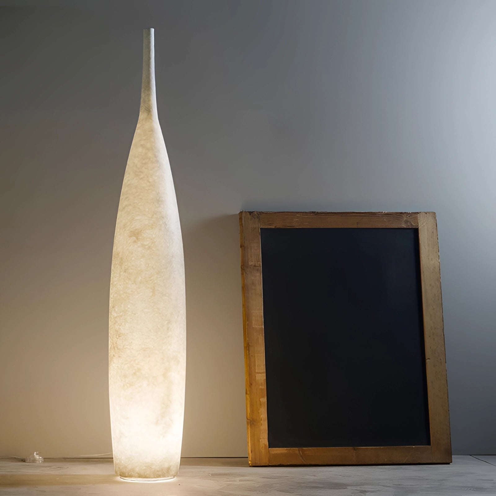 Tall narrow white ceramic vase with a distressed finish, embodying Scandinavian minimalist design, placed against a simple backdrop.