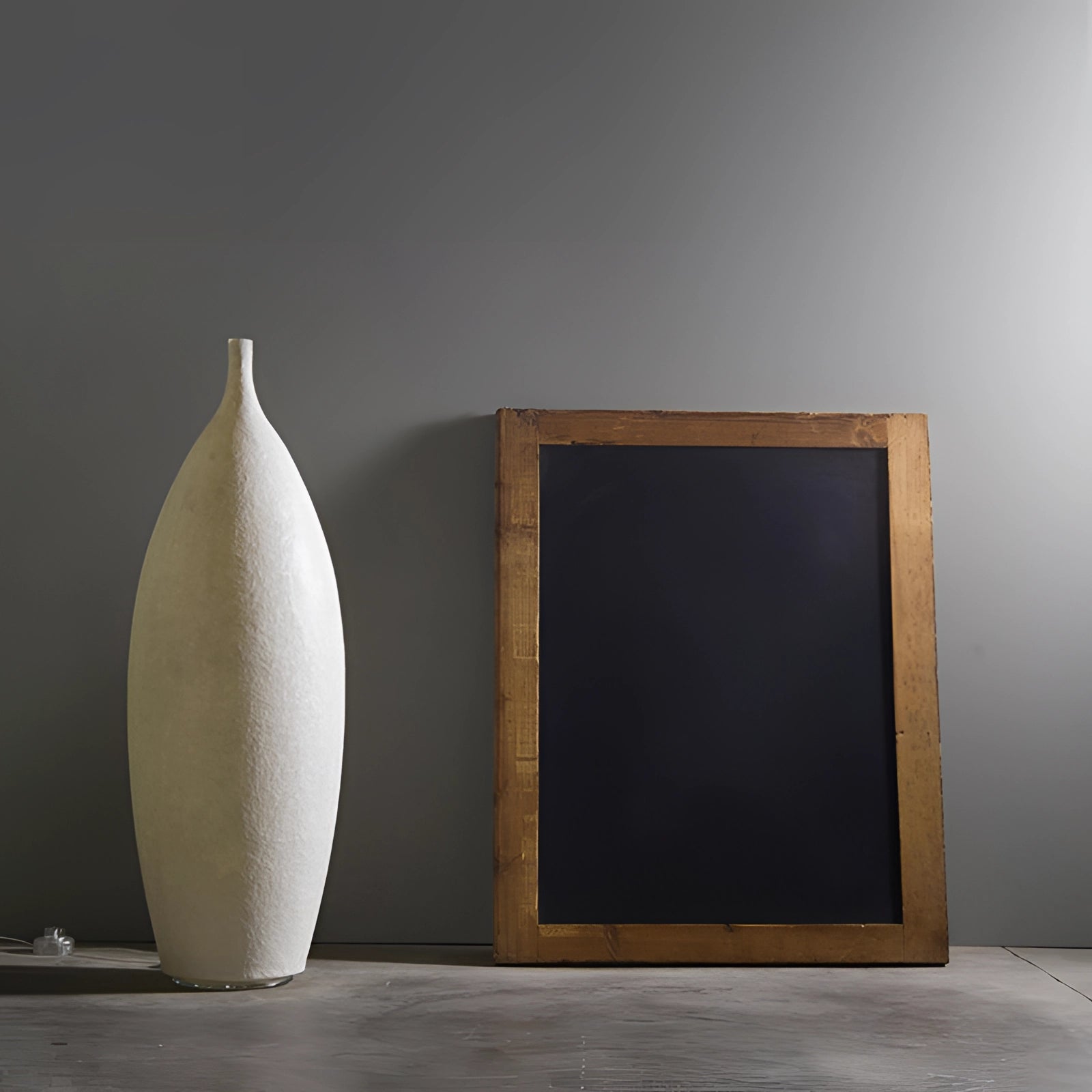 Tall narrow white ceramic vase with a Scandinavian minimalist design and a distressed finish, measuring 36.5 inches, placed against a wooden backdrop.