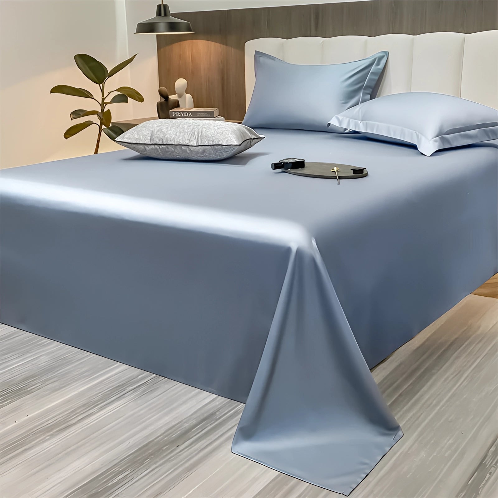 Luxurious light blue silky bed sheets in a modern minimalist bedroom setting, showcasing their smooth and comfortable texture, elegantly draped over a large bed measuring 245x265cm.