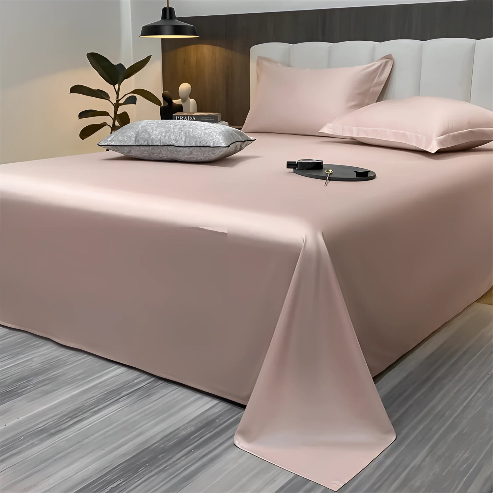 Sea green silky luxury bed sheets in a light pink color, draped over a bed in a modern minimalist bedroom setting, featuring a spacious 245x265cm size. The room showcases elements of interior design with wooden flooring and a well-lit, comfortable atmosphere.