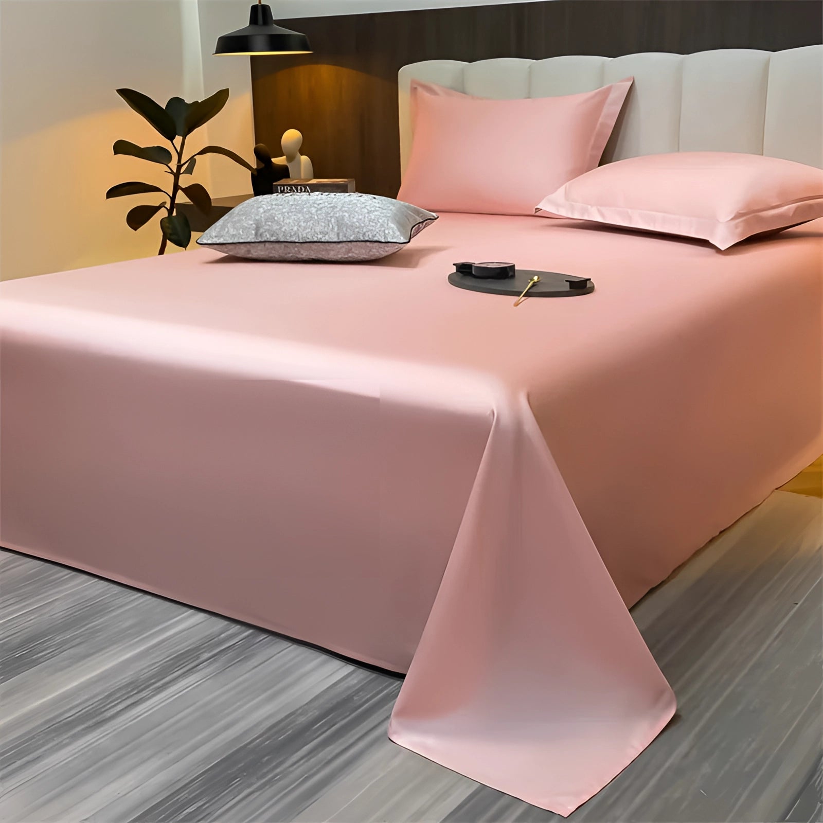 Sea green silky luxury bed sheets in a modern minimalist bedroom setting, featuring a pink variant in size 245x265cm, with warm lighting and a wooden floor.