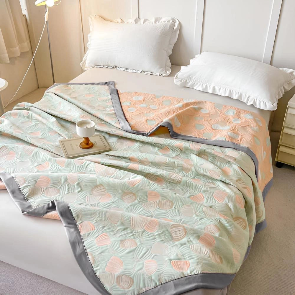 Ocean-inspired duvet cover with pastel beach-themed seashell patterns on a neatly made bed, accompanied by matching pillows, on a hardwood floor.