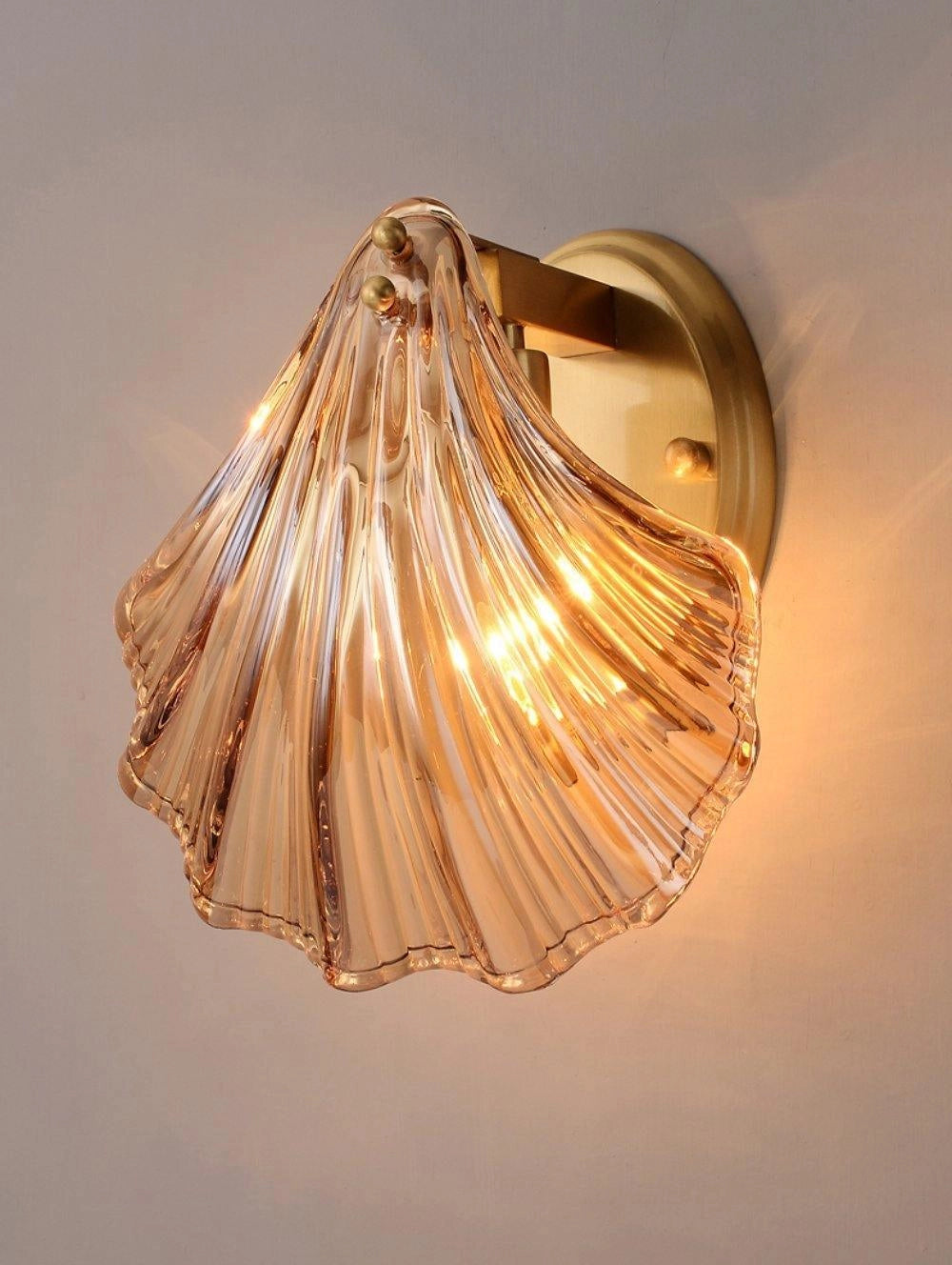 Gold nautical coastal seashell wall sconce light fixture with amber-tinted metal and wooden accents.