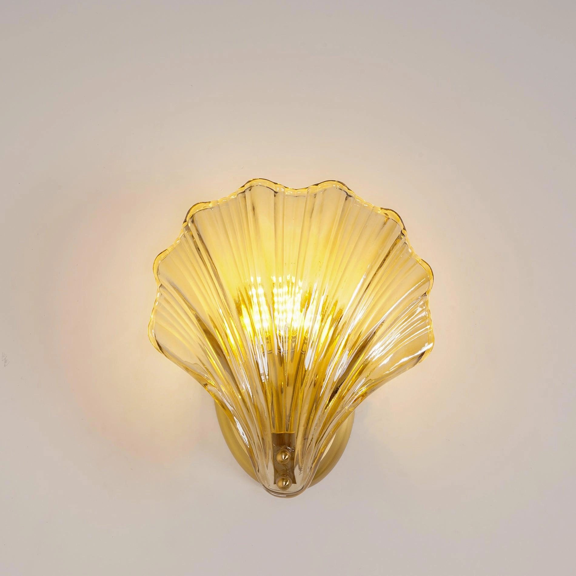 Gold Shell Wall Sconce with Nautical Coastal Seashell Design, featuring detailed craftsmanship and artistic touches, mounted on a wall with surrounding decor including artificial flowers and a glass vase.