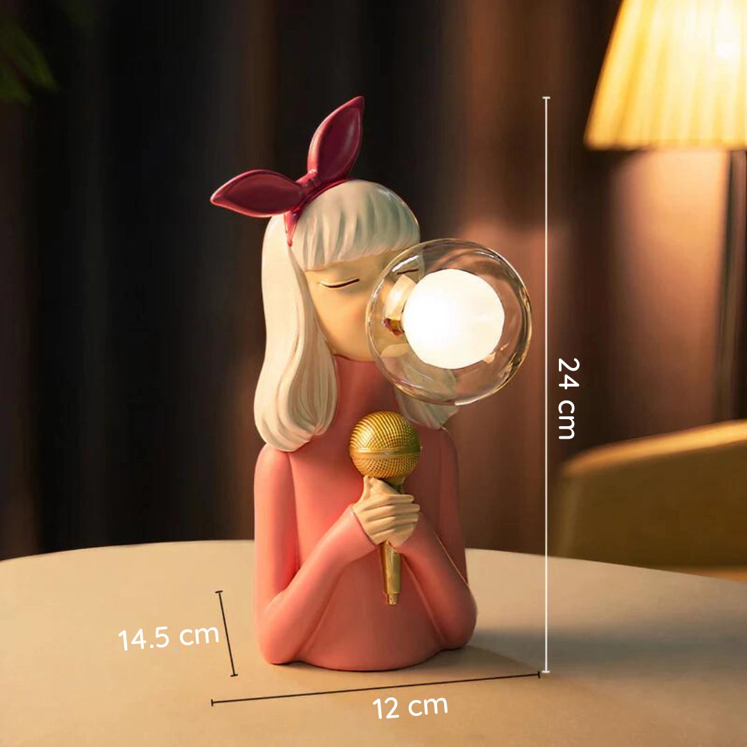 Singer Figurine Desk Lamp in Lily variant featuring a cartoon-style design with long hair, a decorative head resembling a fictional character, and elements of plant motifs, set on a wooden base.