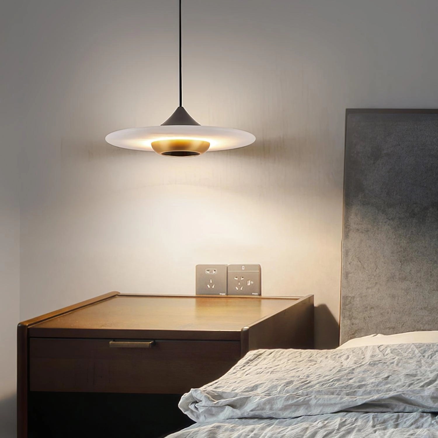 Sleek black LED pendant light hanging above a wooden table in a modern minimalist interior, casting a warm glow and complementing the grey walls and comfortable decor.
