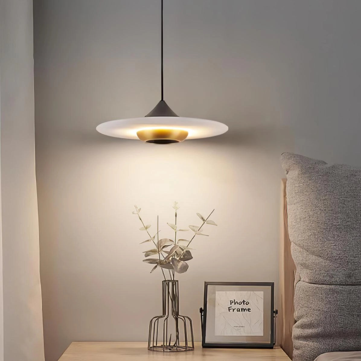 Sleek black LED pendant light with a modern minimalist design hanging above a wooden table in a grey-toned interior setting.