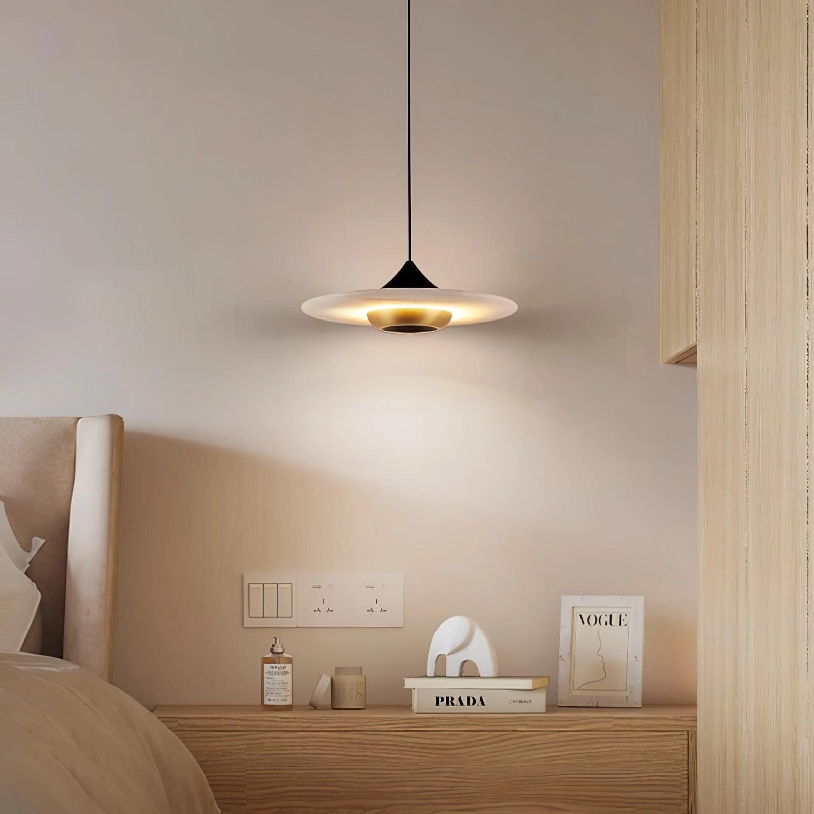 Sleek black LED pendant light hanging from a ceiling, illuminating a modern minimalist interior space with beige and wood elements, featuring comfortable furnishings and wooden flooring.