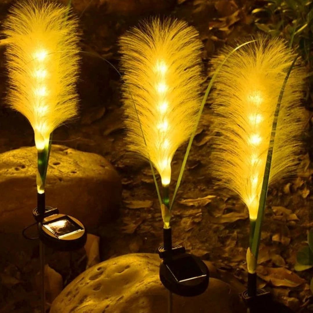 Solar Feather Garden Light illuminating a garden scene at night, with warm LED glow resembling a feather, surrounded by trees and foliage, creating a serene outdoor ambiance.