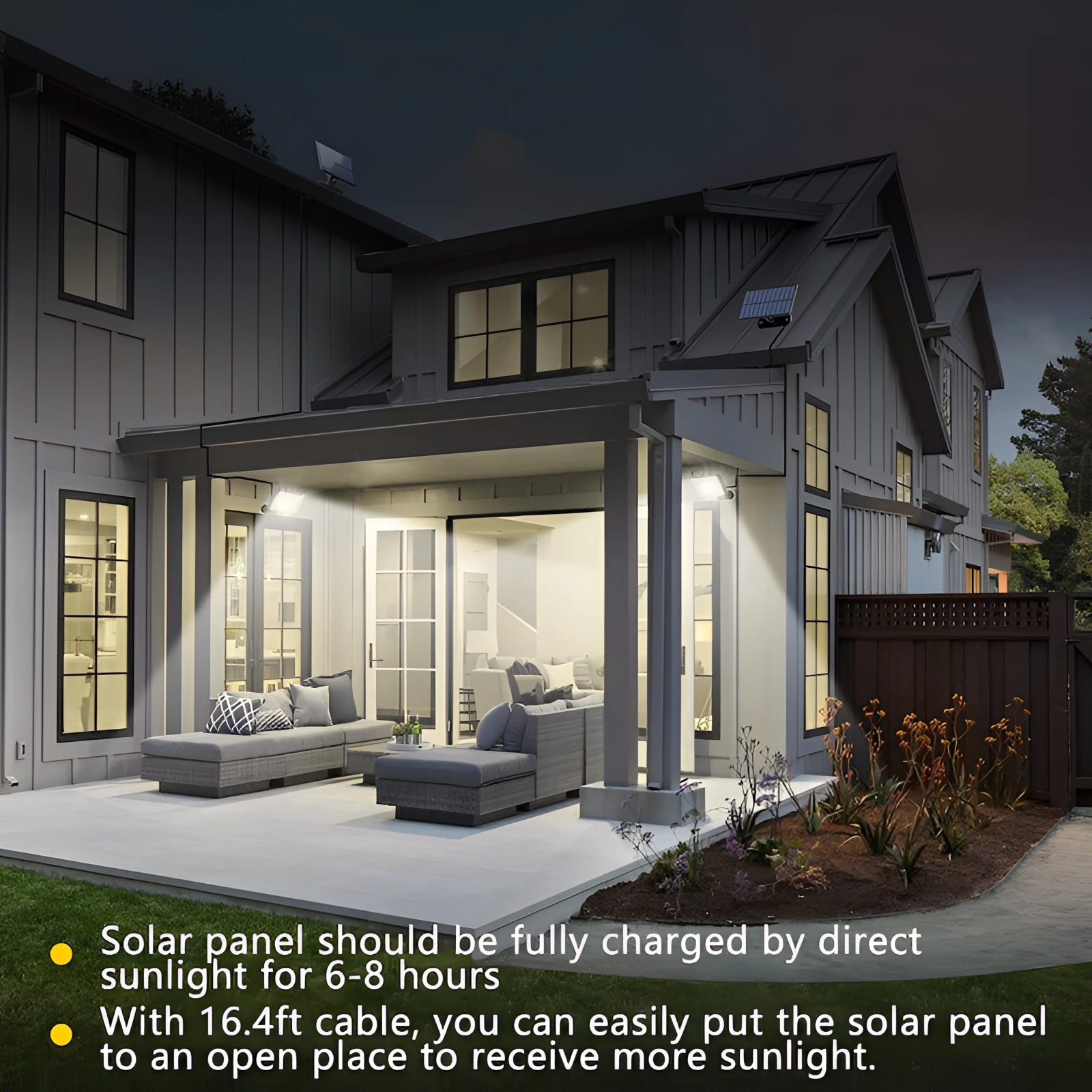 Solar LED motion-sensor security floodlight mounted on the exterior of a residential building, with the device facing towards a neat facade and surrounded by plants under a clear sky.