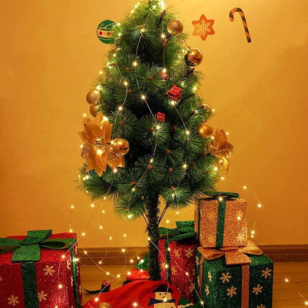 Solar powered outdoor LED fairy lights wrapped around a Christmas tree adorned with red holiday ornaments, creating a festive and eco-friendly decoration in an outdoor setting.