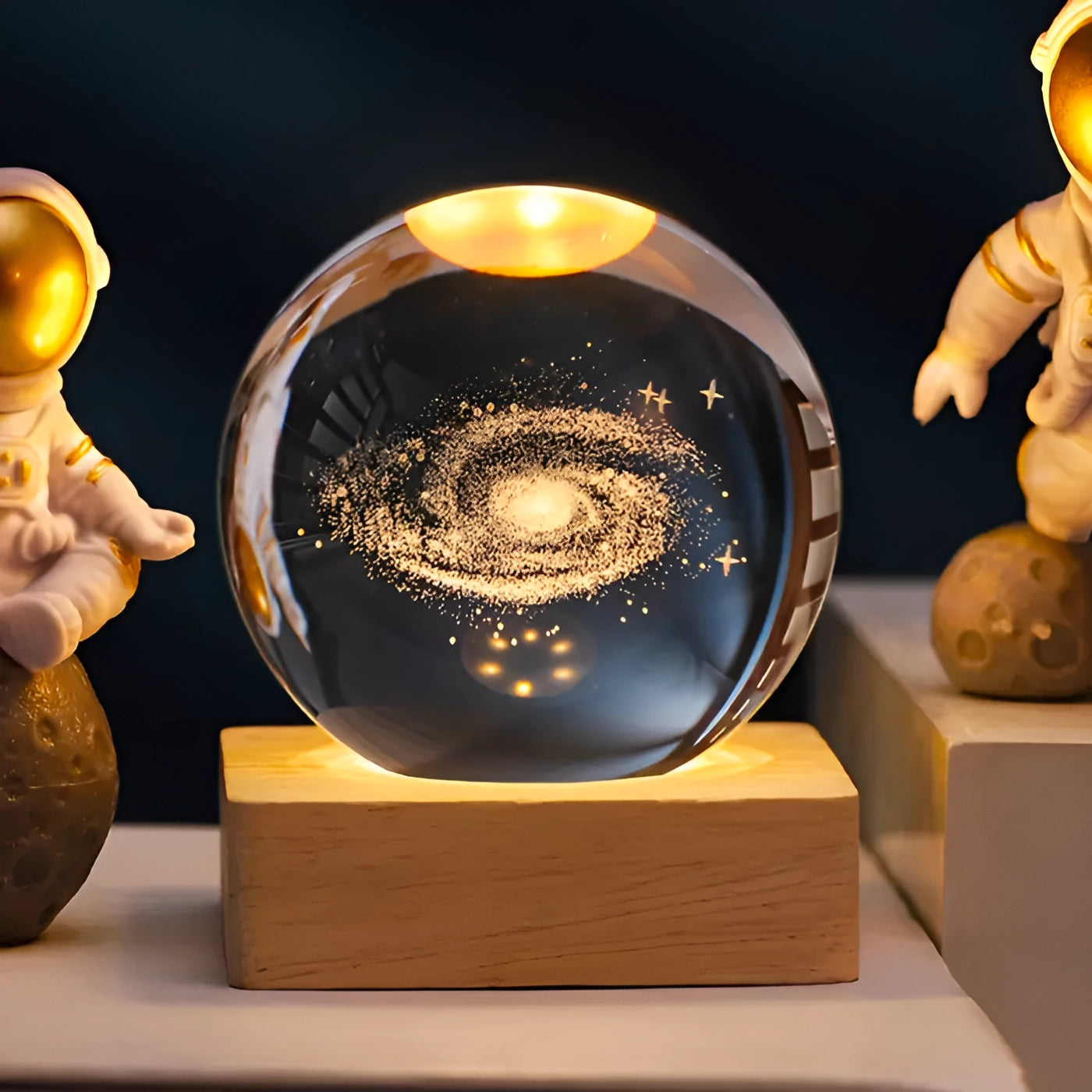 3D engraved crystal ball depicting a model of the solar system, placed on a round LED base. The crystal ball features a galaxy design, showcasing intricate details of planets and stars. The base complements the artwork, enhancing its visual appeal.