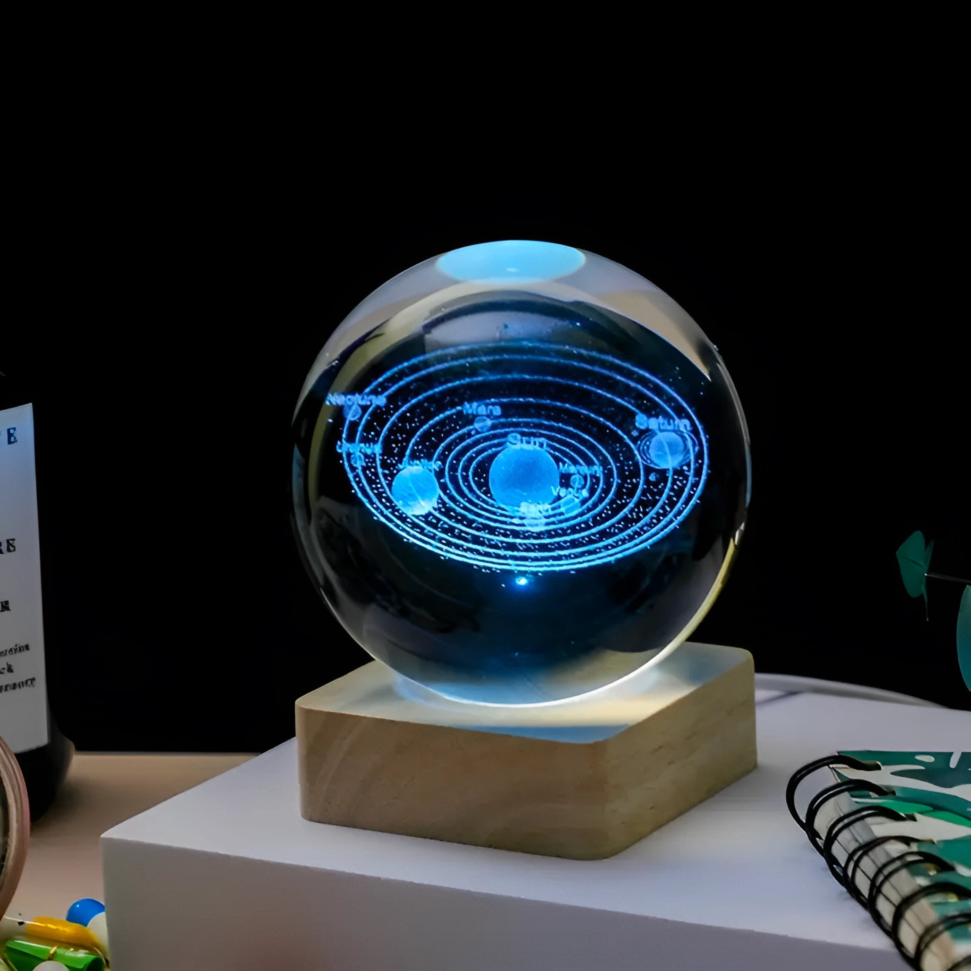Crystal ball featuring a 3D engraved model of the solar system with a LED base, displaying an electric blue glow, designed for visual effect lighting, perfect for space and science enthusiasts.