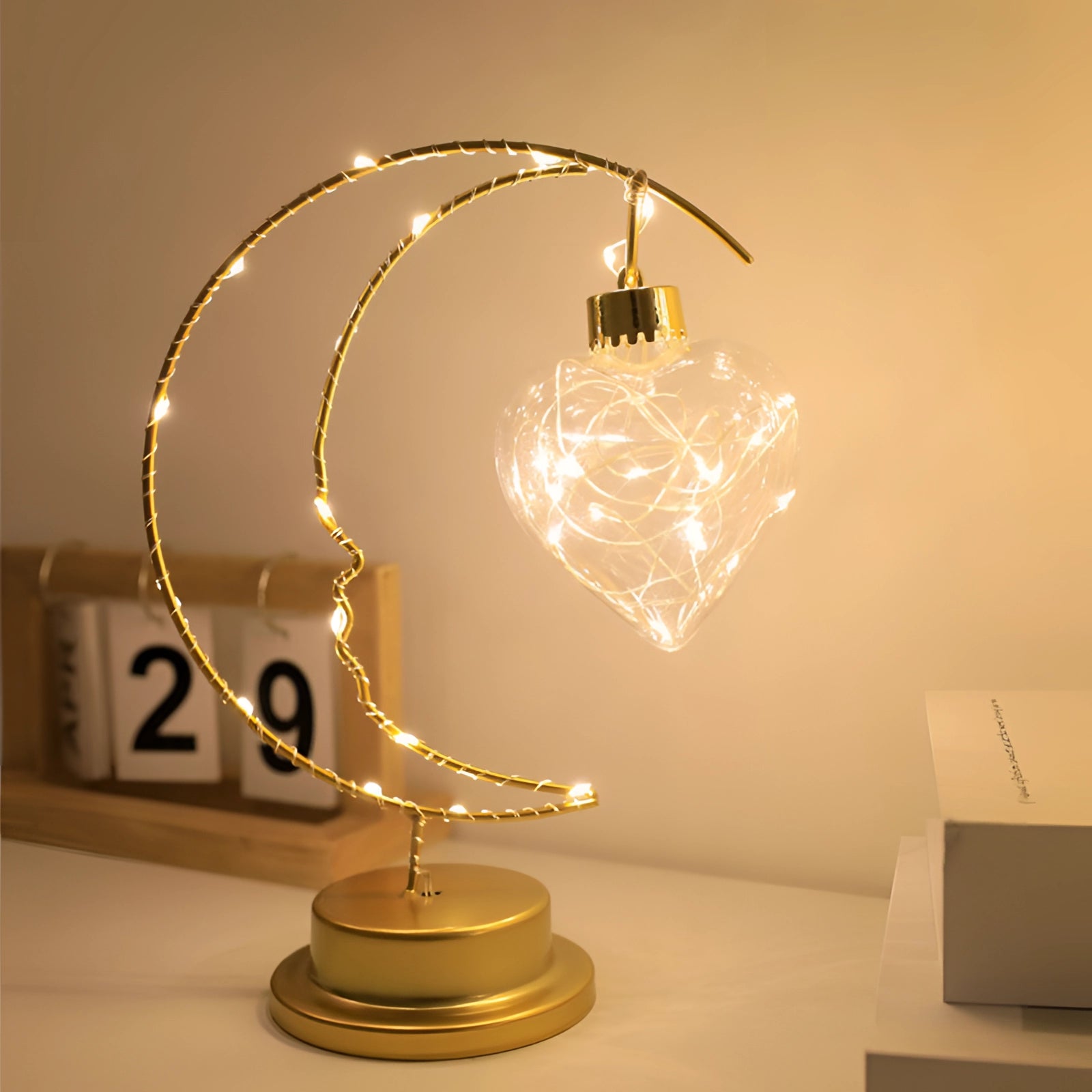 StarryGleam USB LED Star & Crescent Moon Night Light featuring a heart design, emitting a warm amber glow. The night light is shaped like a crescent moon with a star, designed as an ornamental piece similar to a chandelier, ideal for adding an artistic touch to bedroom decor.