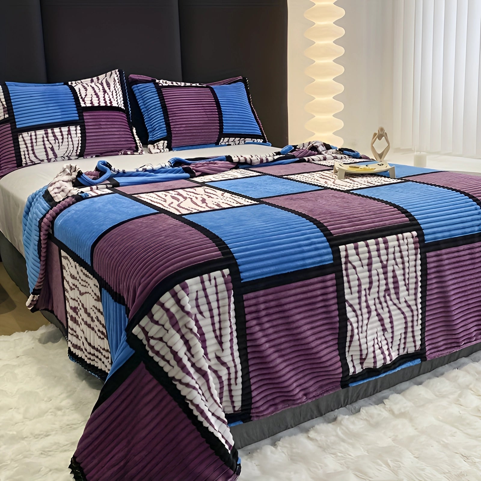 Striped bedding set with a modern geometric quilt pattern in shades of blue and azure, displayed on a neatly made bed with matching pillows and bed skirt in a contemporary bedroom setting.