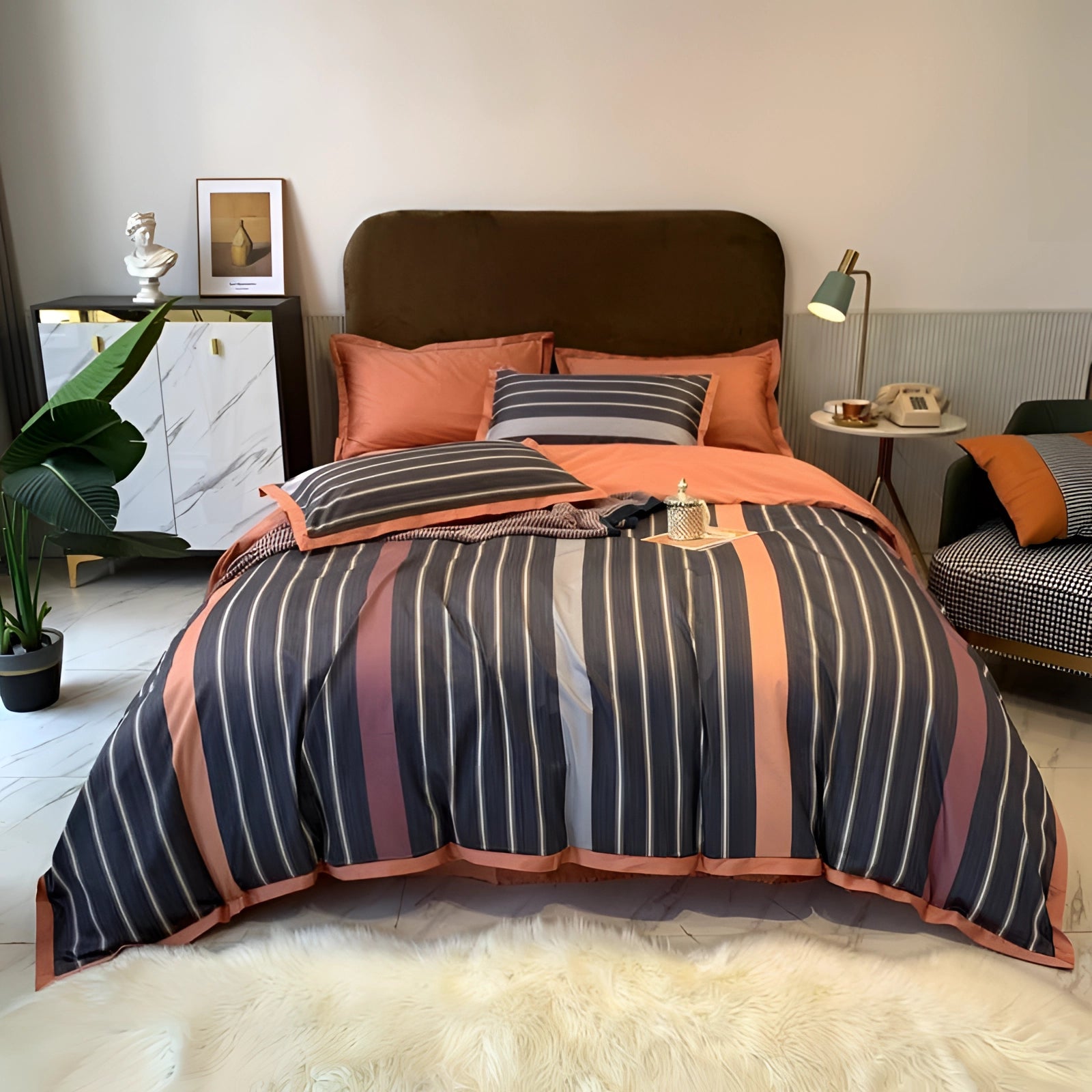 Striped navy and coral luxury bedding set in a king size, displayed in a modern bedroom setting with a focus on comfort and interior design, featuring wood flooring and a houseplant for added ambiance.