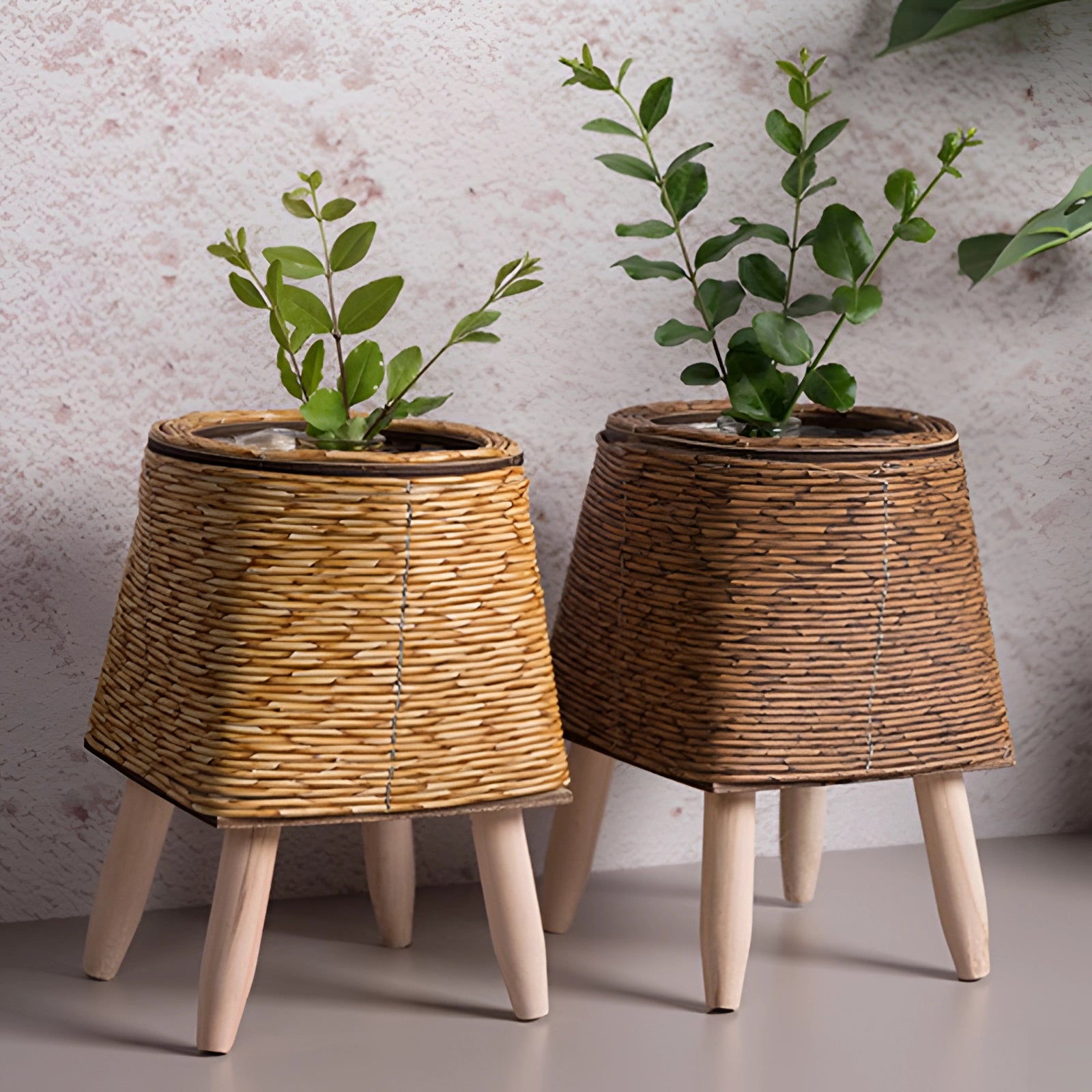 Stylish rectangular wicker planter with bamboo stand and legs, featuring a green plant, suitable for both indoor and outdoor use.