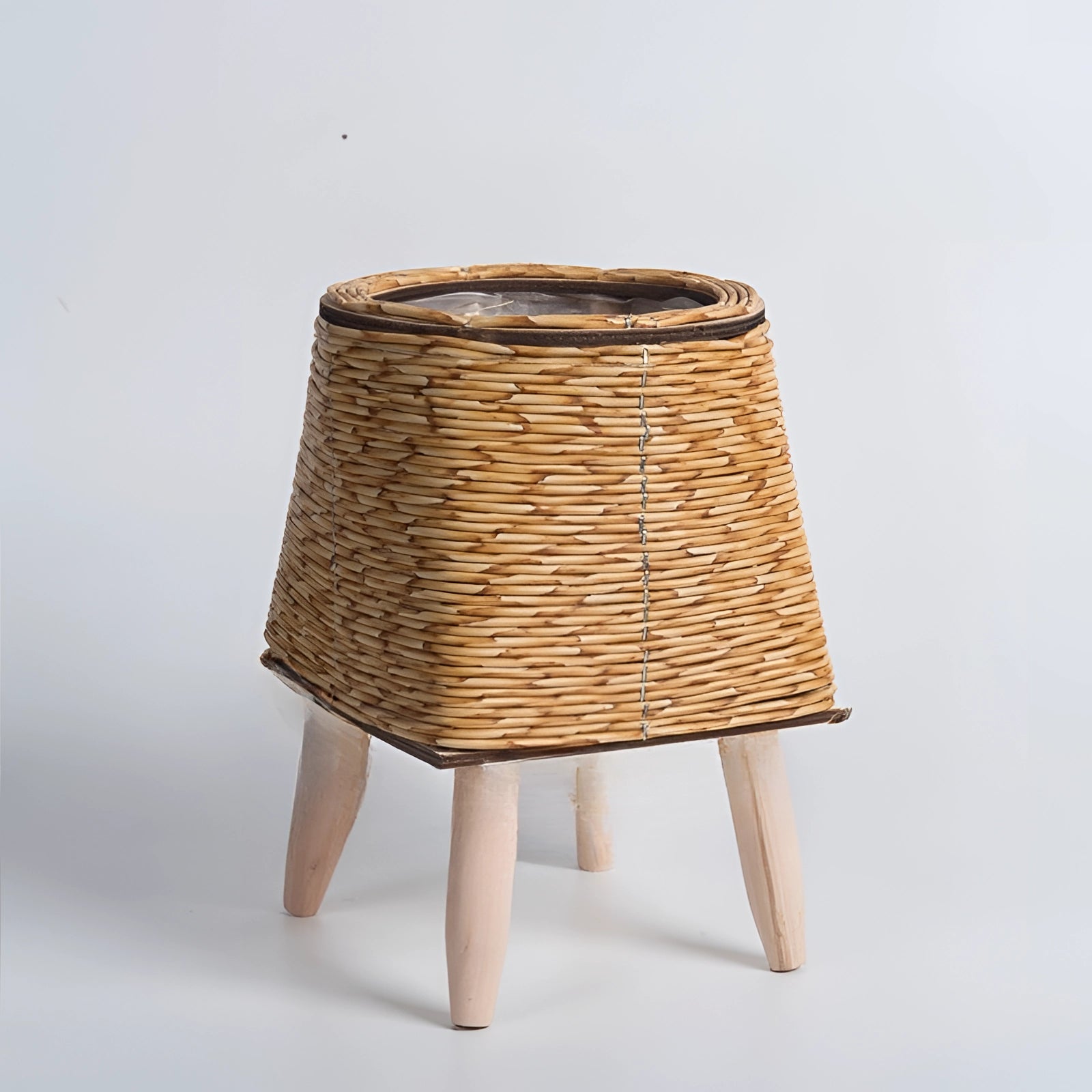 A rectangular wicker planter with a bamboo stand and legs, showcasing an eco-friendly design. The planter is positioned indoors, highlighting its stylish and natural aesthetic with a wood finish.
