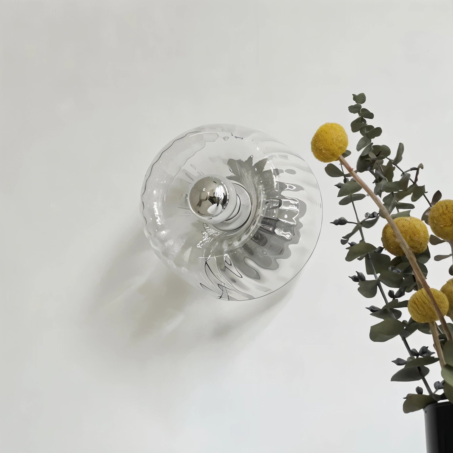 Sunburst ceiling light with a modern gold radial pattern, featuring metal and glass elements, displayed above a decorative plant.