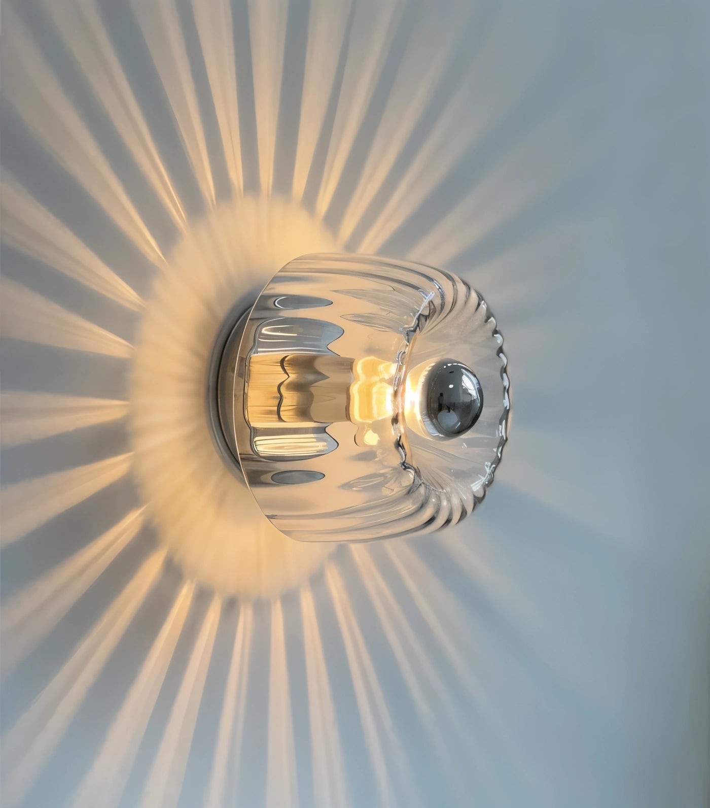Modern gold radial pattern ceiling light fixture with a sunburst design, featuring a circular metal frame, mounted on a ceiling, enhancing contemporary interiors.
