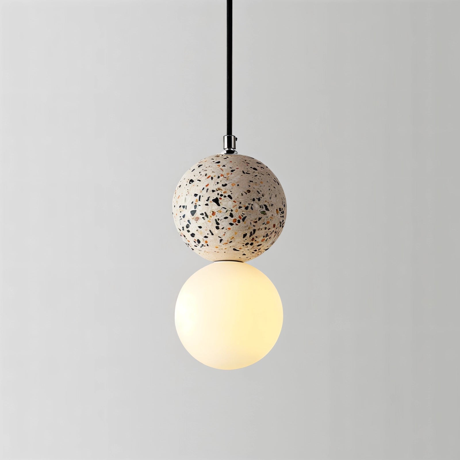 White terrazzo spherical pendant light made of minimalist concrete, featuring a smooth circular design with metallic accents, hanging from the ceiling as a stylish and modern fixture.