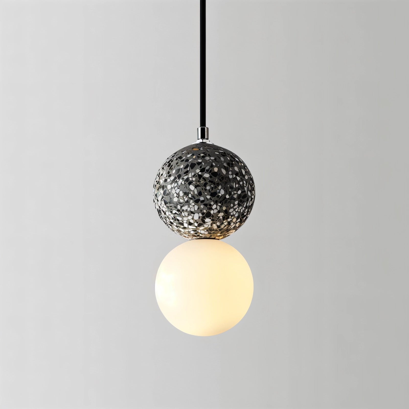 Gray terrazzo spherical pendant light made of minimalist concrete with a circular pattern and metal accents, designed as a ceiling fixture.
