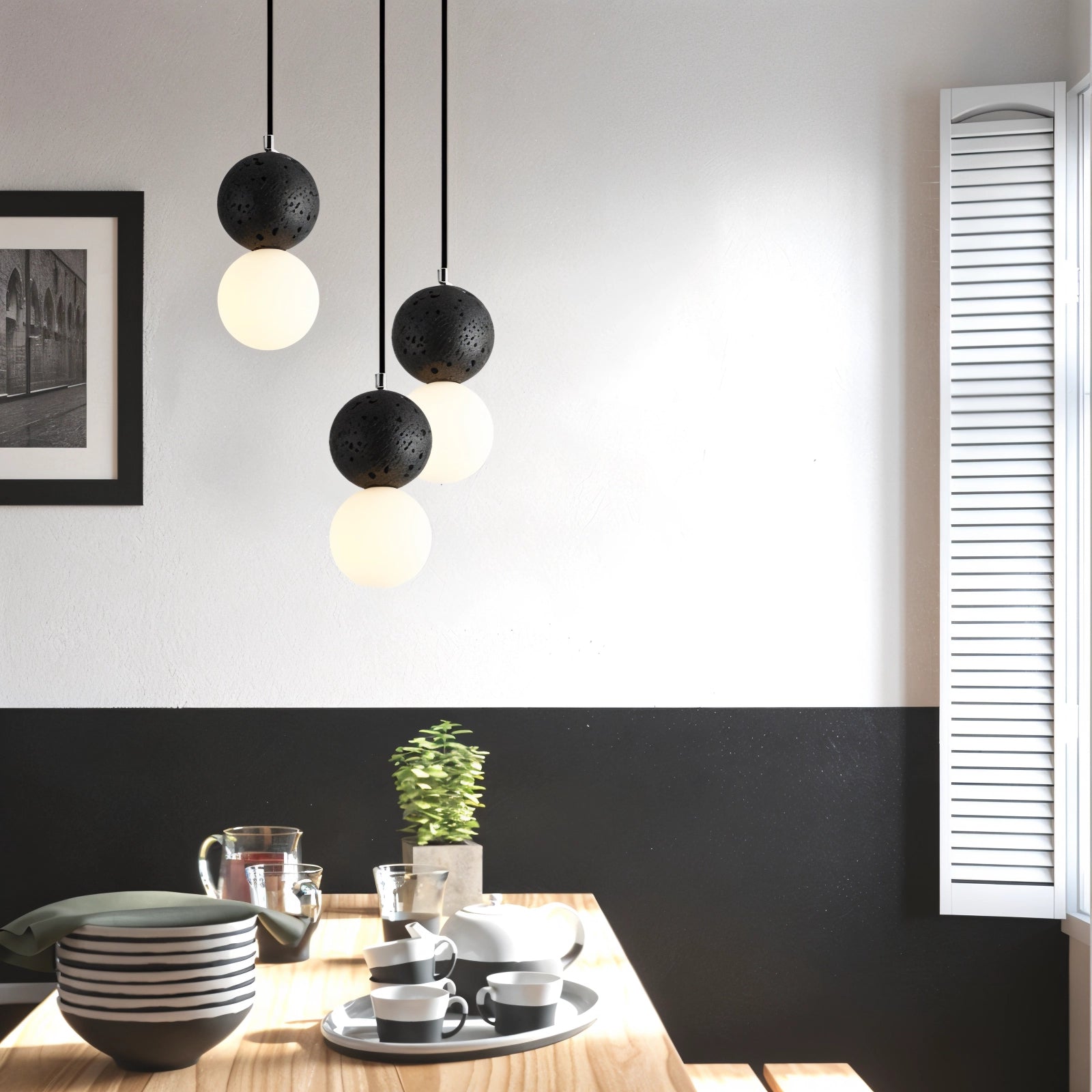 A minimalist terrazzo spherical pendant light made of concrete, hanging above a modern dining table setting with white and black tableware and a cup.