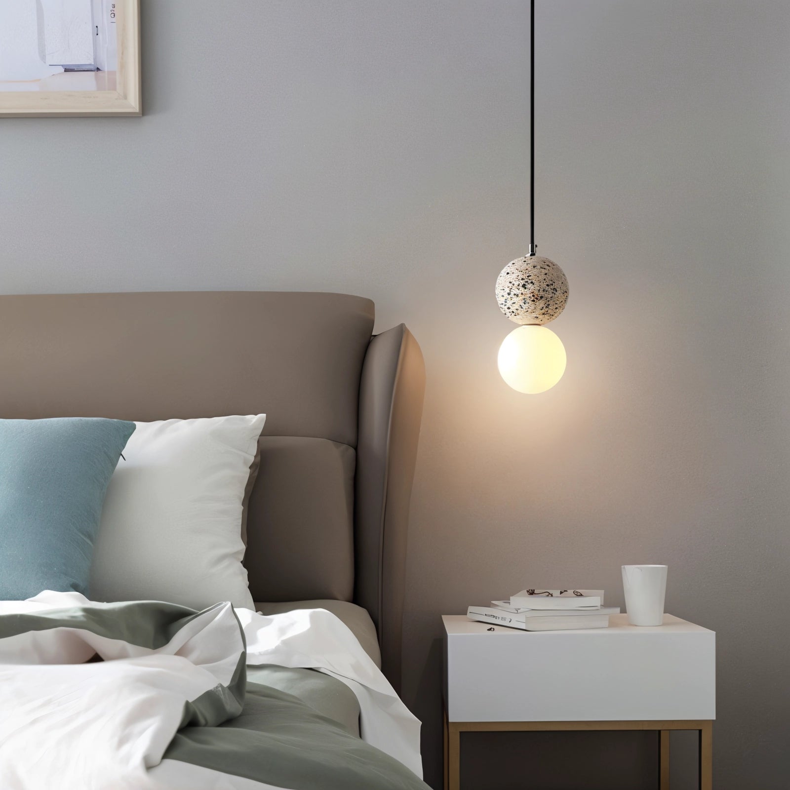 Terrazzo spherical pendant light with a minimalist concrete design hanging above a white and wood table in a modern interior setting.