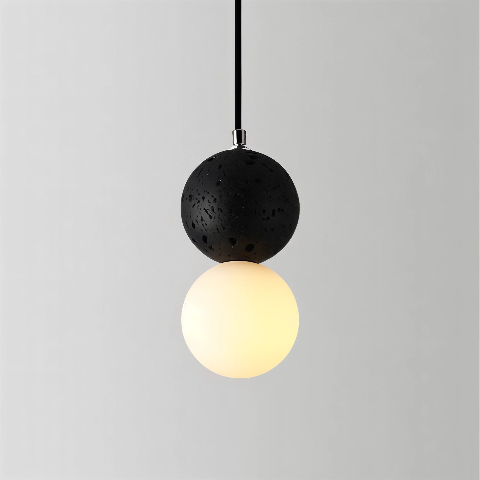 Black terrazzo spherical pendant light with a minimalist concrete design, hanging from the ceiling as a modern light fixture.