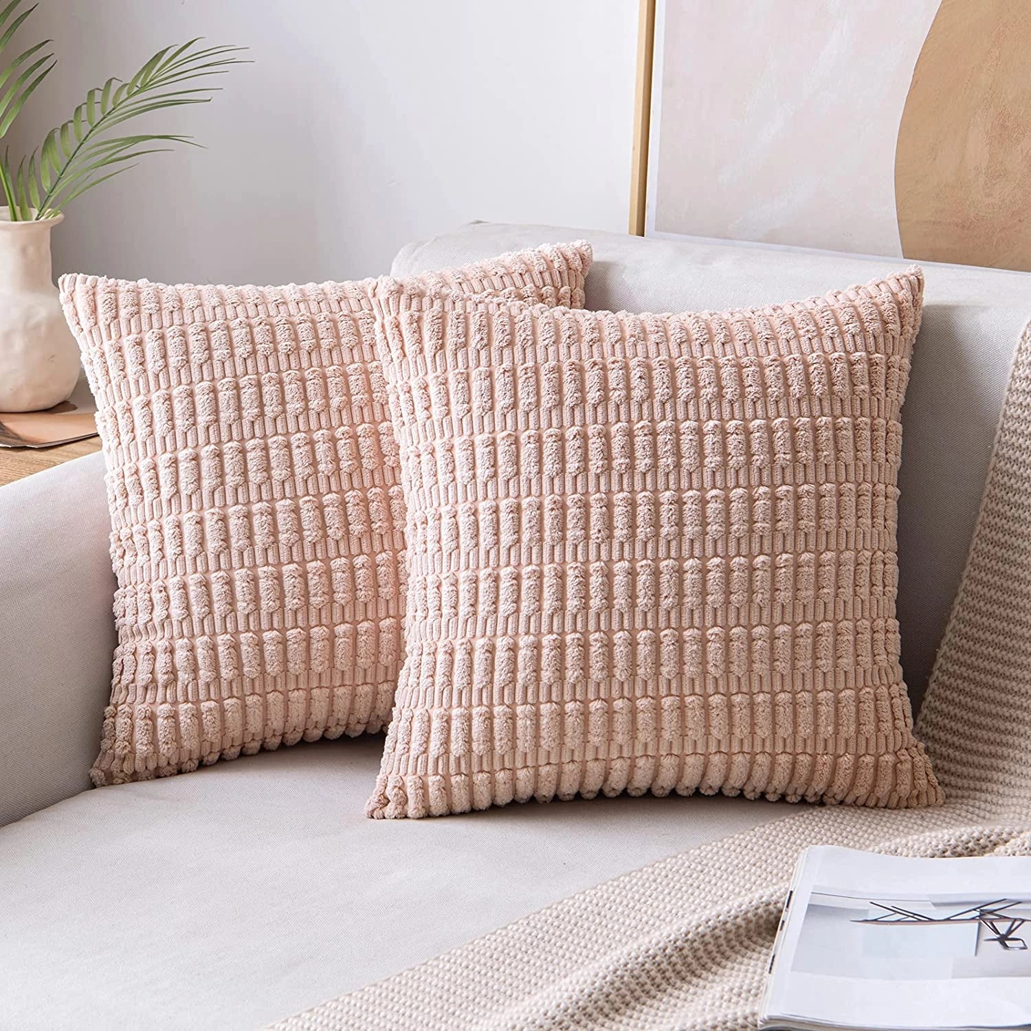 Textured corduroy cushions in a rose color displayed on a beige sofa, showcasing a set of 45x45cm rectangular pillows as part of a stylish interior design, with elements of wood and plants in the background for added comfort and aesthetic appeal.